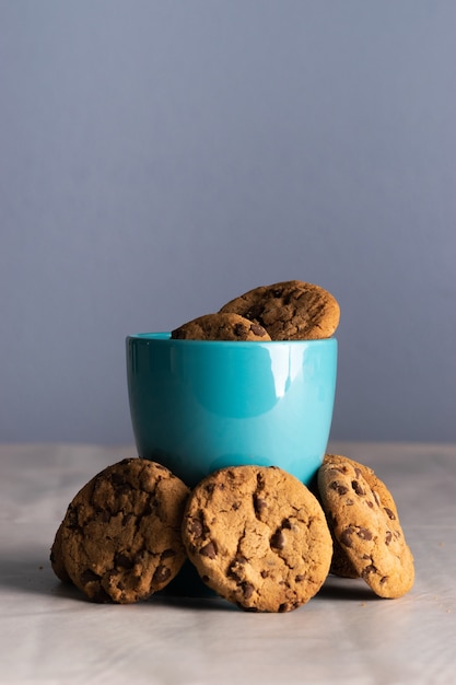 Verticale shot van een blauwe mok melk en chocoladeschilferkoekjes eromheen