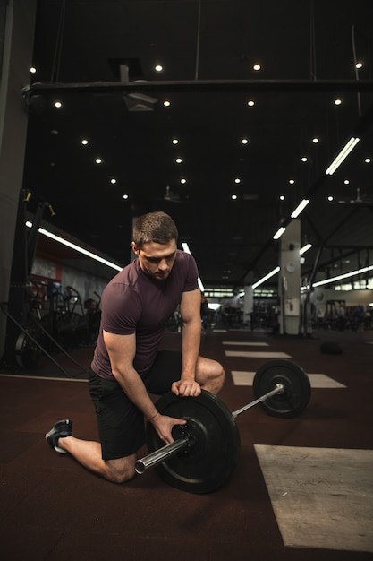 Verticale shot van een gespierde mannelijke atleet die traint met zware barbell in de sportschool