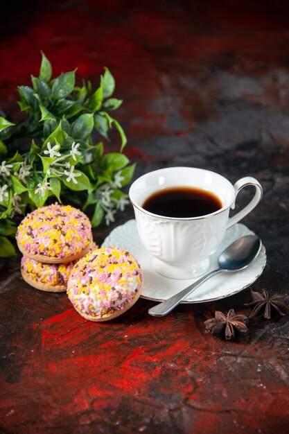 Verticale weergave van zelfgemaakte heerlijke suikerkoekjes en een kopje koffiebloempot op donkere mixkleurenachtergrond met vrije ruimte