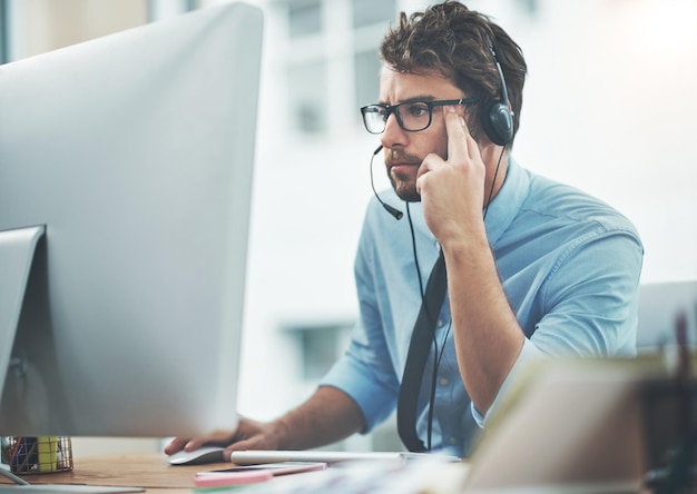 Vertrouw hem om het antwoord te vinden Shot van een jonge man die in een callcenter werkt