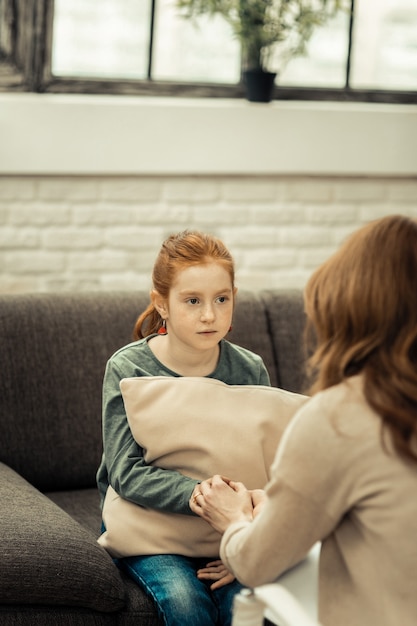 Vertrouwen ontwikkelen. vrolijk jong meisje dat tegenover haar therapeut zit terwijl ze haar een hand geeft