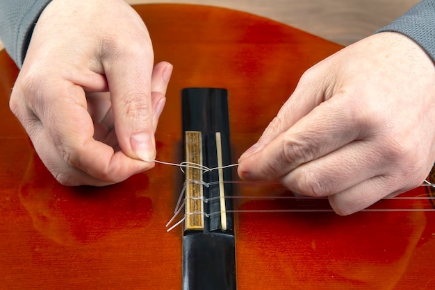 Vervanging en inbrengen van nylon snaren in een klassieke gitaar. les voor een muzikant