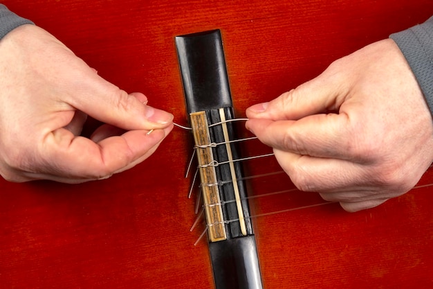 Vervanging en inbrengen van nylon snaren in een klassieke gitaar. les voor een muzikant