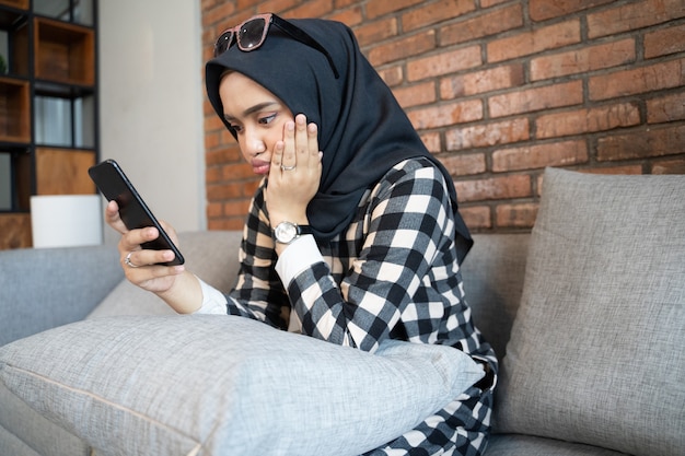 Verveeld vrouw thuis met behulp van haar mobiele telefoon