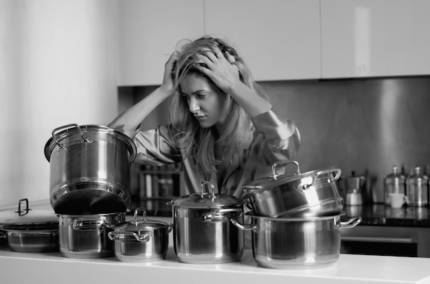 Verveelde huisvrouw op de ochtend huishoudelijk werk boze vrouw zitten in de keuken en koken eten met