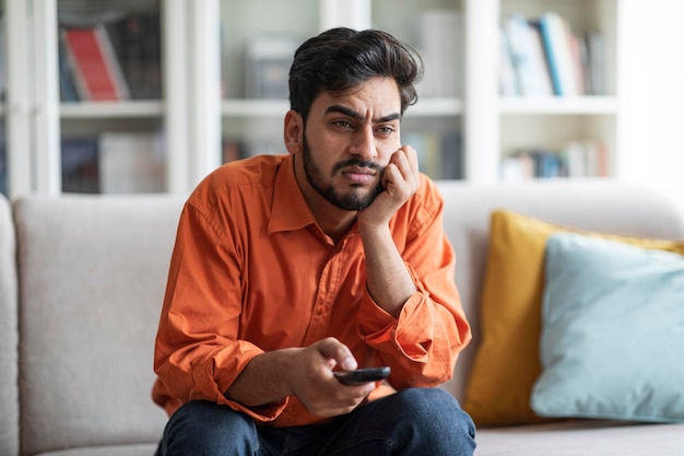 Verveelde man uit het Midden-Oosten die thuis zit en van tv wisselt