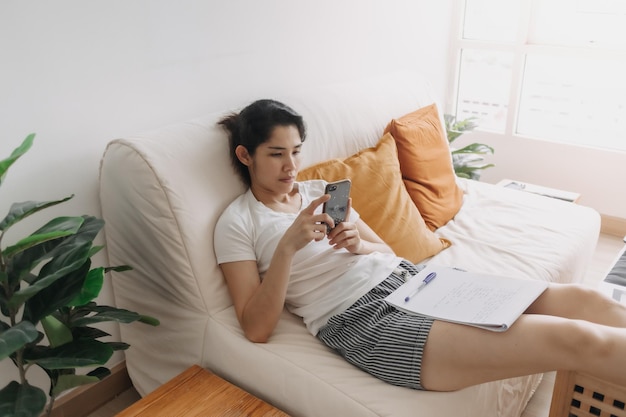 Verveelde vrouw gebruikt sociale media op smartphone om tijd in appartement te doden