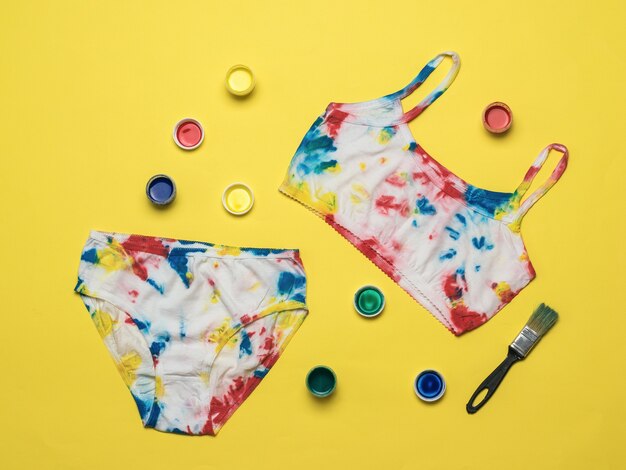 Verven en lingerie in de stijl van tie dye op een gele achtergrond. Gekleurd ondergoed in huis.