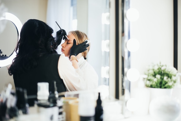 Verven en vormgeven van wenkbrauwen. meisje in een schoonheidssalon.