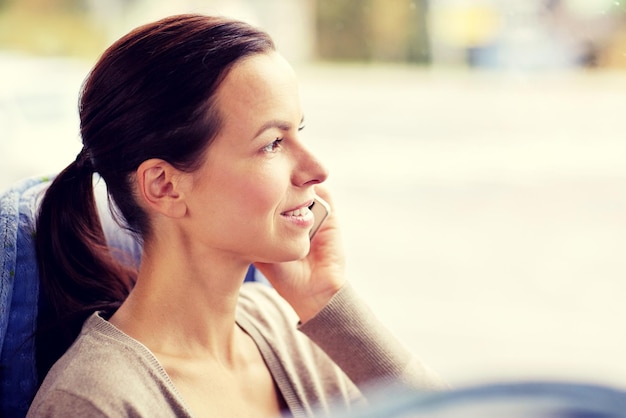 vervoer, toerisme, road trip en mensen concept - gelukkige jonge vrouw in de reis bus of trein bellen op smartphone