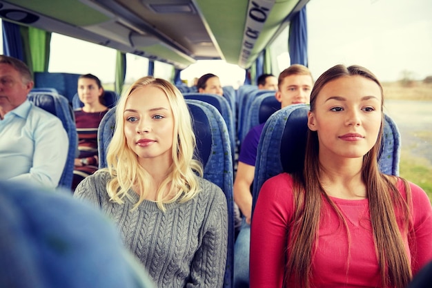 vervoer, toerisme, vriendschap, roadtrip en mensenconcept - jonge vrouwen of tienervrienden die in reisbus rijden