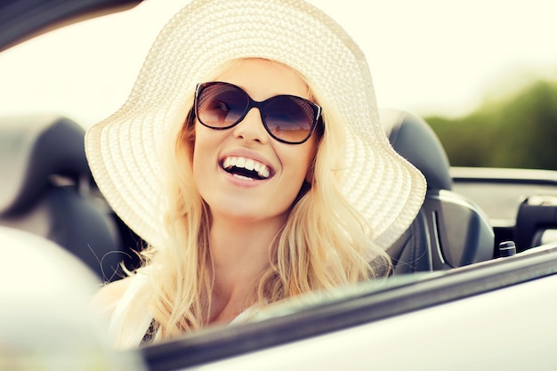 vervoer, vrije tijd en mensenconcept - gezicht van gelukkige vrouw in de zomerhoed en zonnebril die cabrioletauto buiten drijven