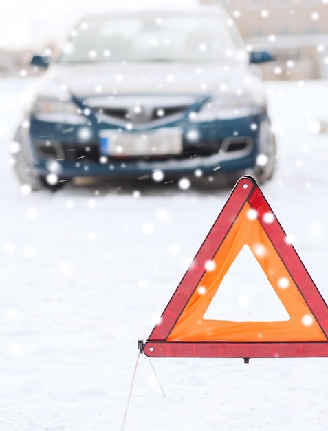 vervoer, winter en voertuigconcept - close-up van gevarendriehoek en auto