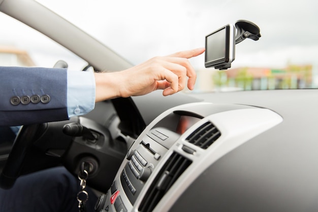 Vervoer, zakenreis, technologie, navigatie en mensenconcept - close-up van mannenhand met gps-navigator tijdens het autorijden