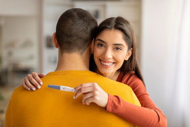 Verwachting van een baby gelukkige vrouw met een positieve zwangerschapstest en een knuffel met haar man