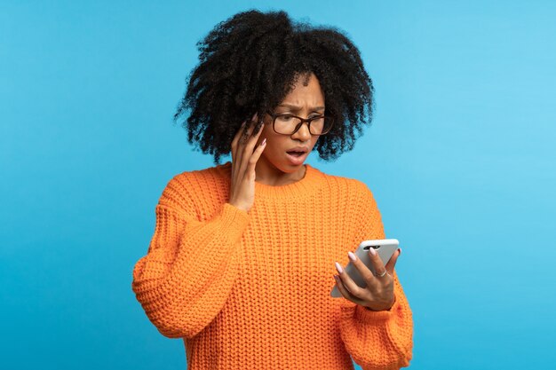 Verward geschokte Afro-vrouw die smartphone bekijkt die slecht nieuws, melding, onaangenaam bericht leest