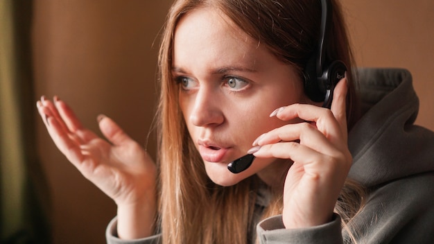 Verward meisjesexploitant met hoofdtelefoons extern werk vanuit huis in een callcenter