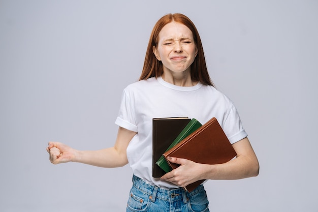 Verward ontevreden jonge vrouw college student boek te houden en schreeuwen camera kijken