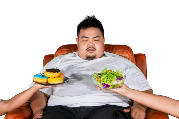 Verwarde man met overgewicht kiest salade of donuts