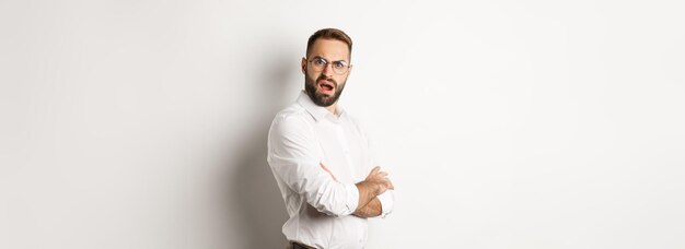 Verwarde manager die naar camera kijkt die geschokt staat tegen een witte achtergrond