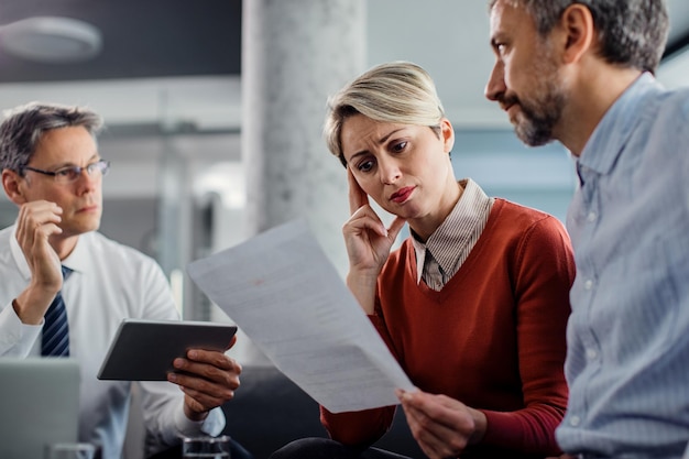 Verwarde vrouw die de voorwaarden van een contract doorneemt tijdens een ontmoeting met een verzekeringsagent