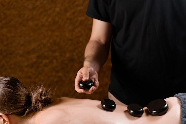 Verwarmde stenen op de rug van de vrouw. Stone massage therapie in de spa om te ontspannen.