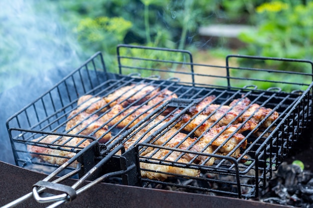 Verwerk het koken van vlezige steak op een barbecue buitenshuis Picknick, buiten eten. Metalen barbecue