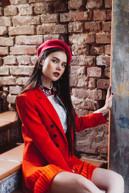 Very beautiful brunette model sitting on the steps on a brick wall background