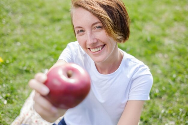 Very beautiful ethnic model eating red Apple in the ParkOutdoors portrait of beautiful young brunette girl in the white hat