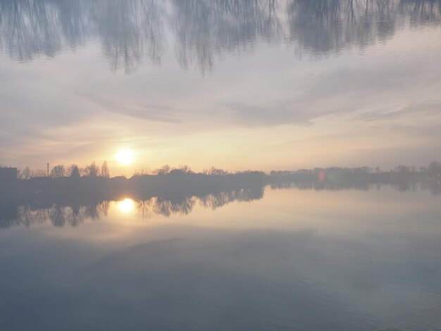 Very beautiful sunset over the water River bank and horizon Bright clouds are painted by the evening sun The descending sun