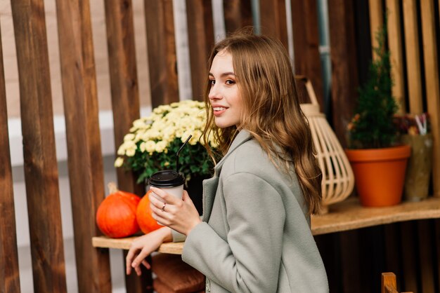 非常に美しい若い女性、カフェに座って、クロワッサンとコーヒーやお茶を飲む