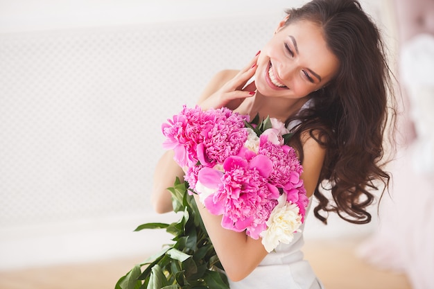 花を持つ非常に美しい若い女性。牡丹と魅力的な少女の肖像画