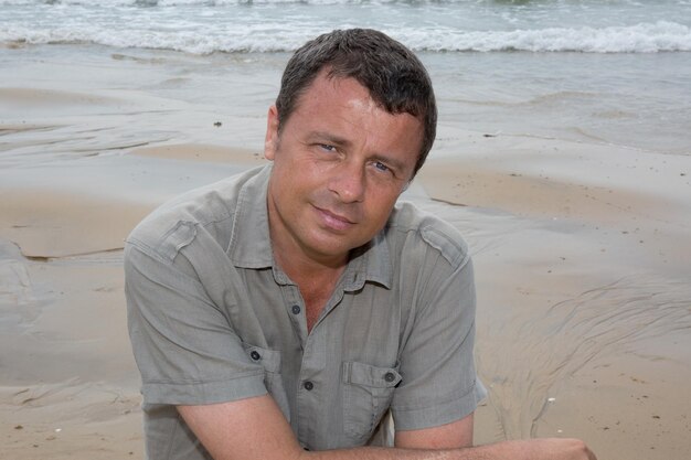 A very charming man at the beach looking at the camera