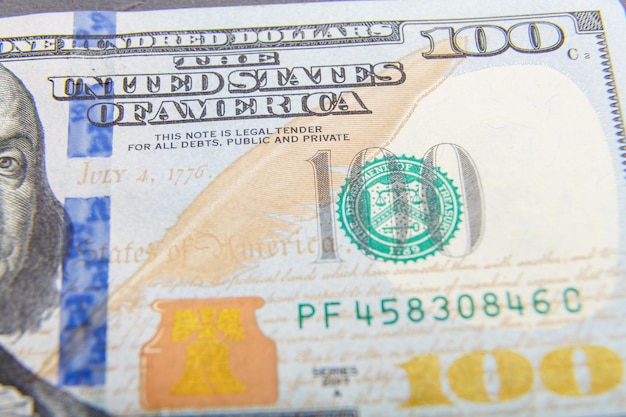 A very close-up of one hundred dollars is spread out on the surface of the table.