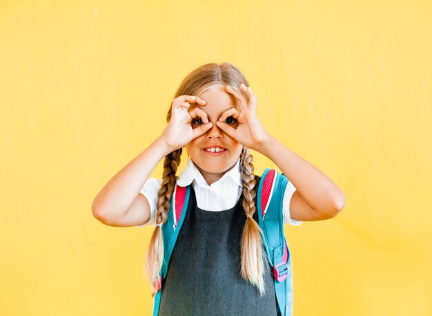 A very cute and funny little girl makes a gesture with glasses with her hands.
