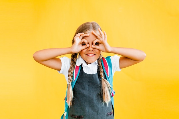 A very cute and funny little girl makes a gesture with glasses with her hands.
