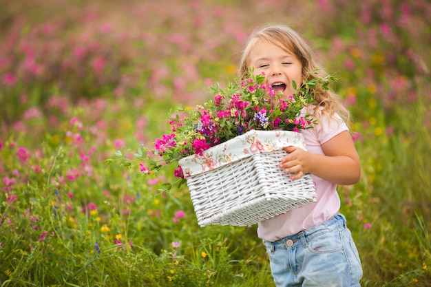 Very cute little emotional girl smiling and screaming with basket full of flowers. Joyful child