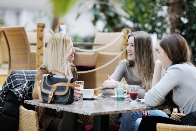 Donne sorridenti molto carine che bevono un caffè seduti all'interno nel ristorante caffetteria