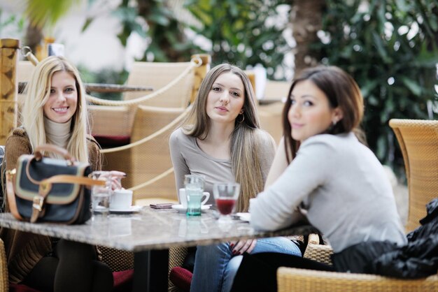 very cute smiling women drinking a coffee sitting inside in cafe restaurant