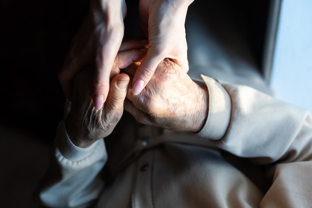 very elderly great-grandmother and granddaughter hold hands