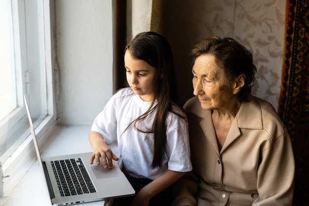 very elderly great-grandmother and granddaughter with laptop online