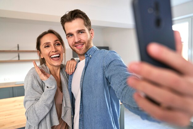 Very excited caucasian couple taking selfie in their new flat