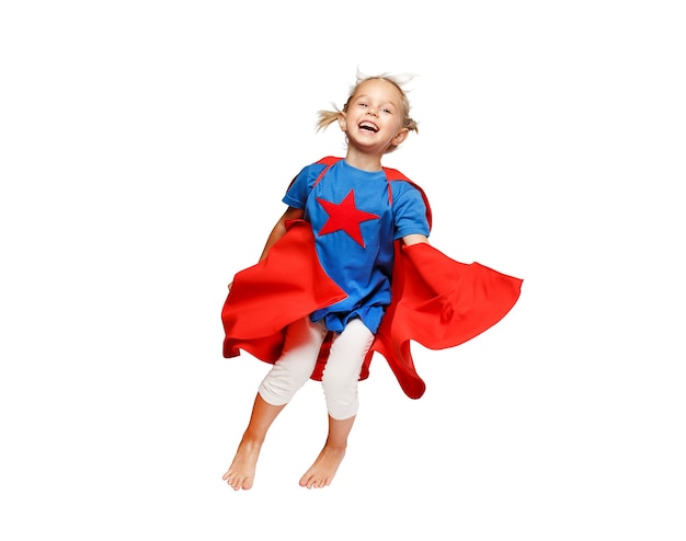 Very excited little girl dressed like hero jumping isolated on white background.