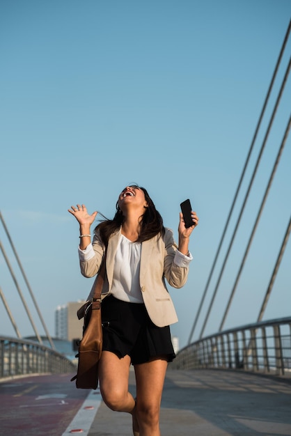 Very excited woman shouts up the street with her hands in the air Copy space