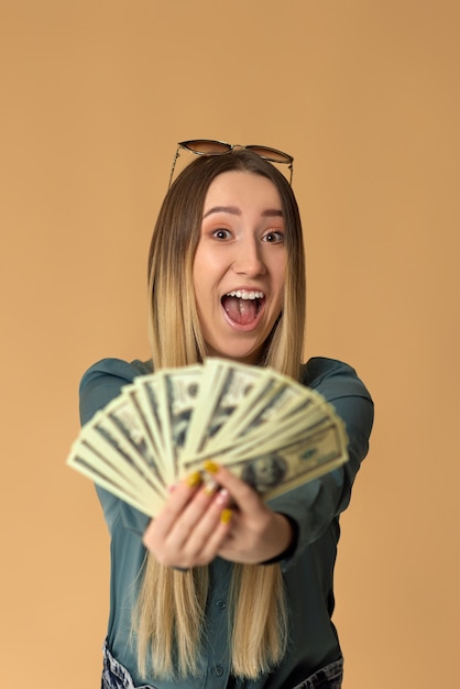 Very excited young woman holds cash money in dollar banknotes. Shopping