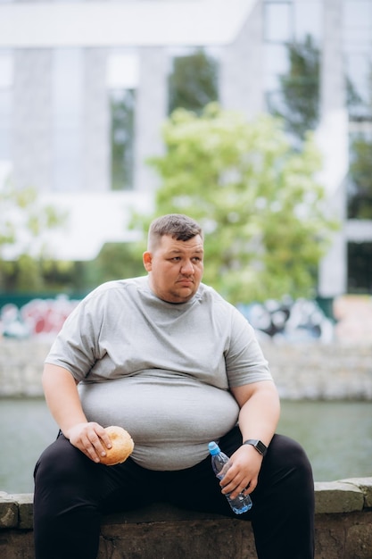 Foto un uomo molto grasso sta mangiando un hamburger