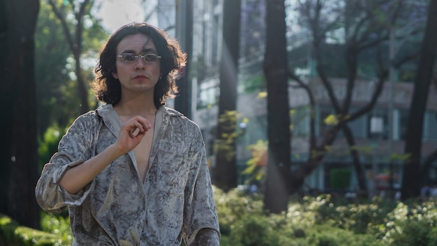 Very handsome gay person walking on the streets in a park in the city, with a bright background.