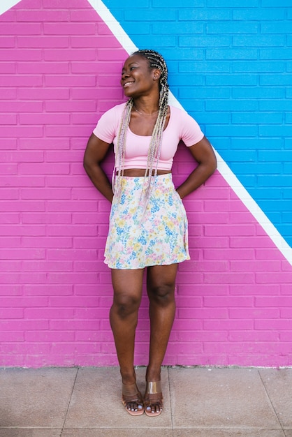 Donna africana nera molto felice che posa su una parete in molti colori. foto a vita di una donna africana felice