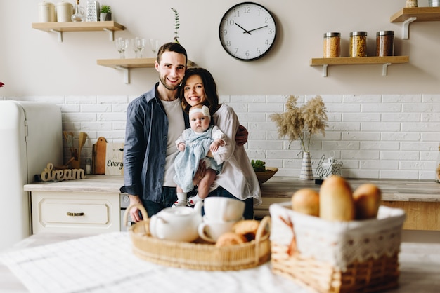 Very happy caucasian family of three in the kitchen of mother, father and baby daughter