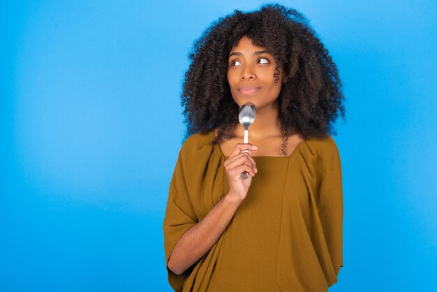 Very hungry model holding spoon into mouth dream of tasty meal